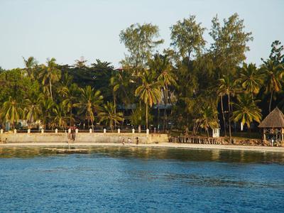 Beach with clear water and palm trees in front of a hotel or resort.