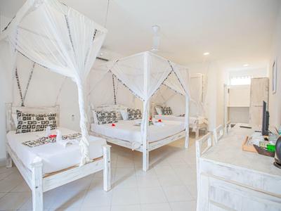 Chambre lumineuse avec deux lits, moustiquaires et décoration minimaliste.