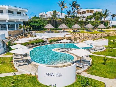 Complex hôtelier moderne avec piscines, parasols et pelouses vertes sous un ciel clair.