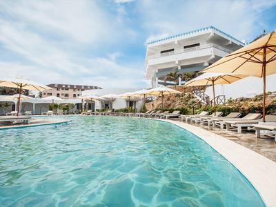 Piscine d'hôtel luxueuse avec parasols et chaises longues sous un ciel dégagé.