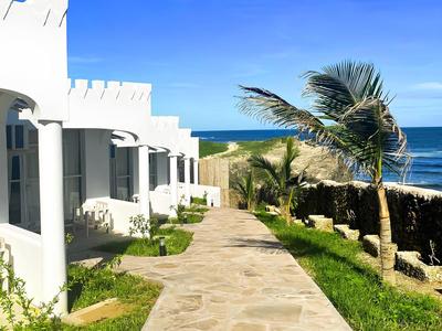 Chemin lumineux à côté de bâtiments blancs avec vue sur la mer et un palmier en vacances