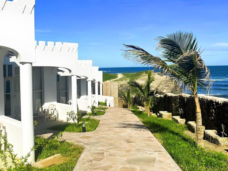 Chemin lumineux à côté de bâtiments blancs avec vue sur la mer et un palmier en vacances