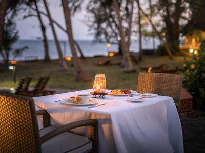 Cena al aire libre con mesa cubierta de blanco con vista a la playa y al mar.