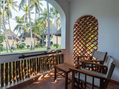 Balcón con muebles de madera con vista a palmeras y bungalós a la luz del día.