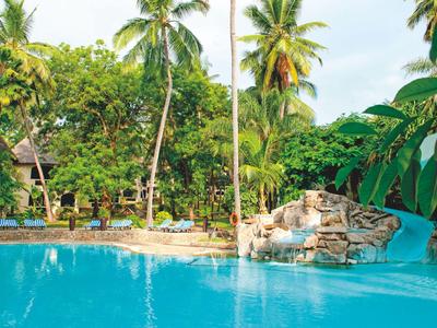 Piscina azul con cascada y tumbonas en jardín tropical del hotel