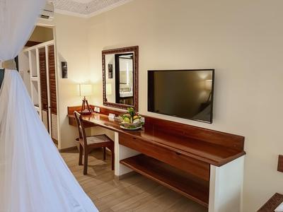 Escritorio elegante con silla, espejo y televisor en la pared en una habitación de hotel.