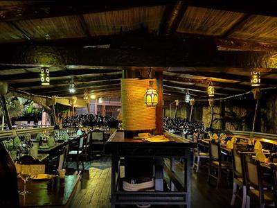 Acogedor bar exterior rústico con techo de madera y luz tenue por la noche.