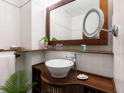 Modernes Hotelbadezimmer mit rundem Waschbecken, großem Spiegel und Holzablagefläche.