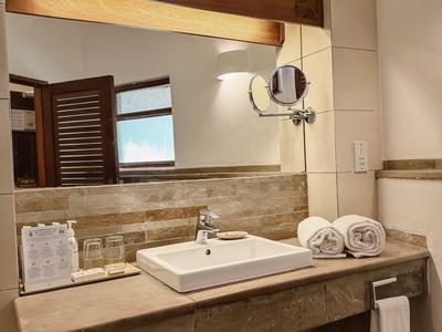 Moderner Hotelbadezimmer-Waschbereich mit Spiegel, Handtüchern und Holzakzenten.