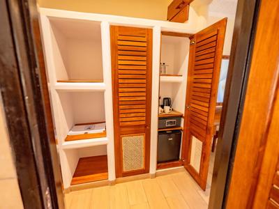Kompakte Küchenzeile mit offenem Holzschrank, Backofen und Regalen in einem Hotelzimmer.