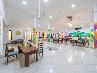 Großer heller Saal mit weißen Wänden, kunstvoll bemalten Säulen und Holzmöbeln.