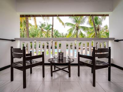Two chairs and a table on a balcony overlooking palm trees.