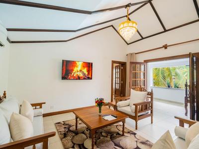Bright living room with wooden ceiling, fireplace on the wall, and open door to balcony with palm view.