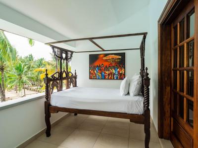 Canopy bed on balcony with tropical view and wall art in white room.