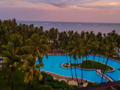 Palm-lined pool with islands by calm sea at sunset