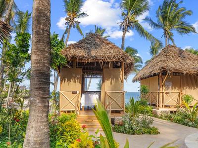 Tropical bungalows with thatched roofs and palm trees on the beach under a blue sky