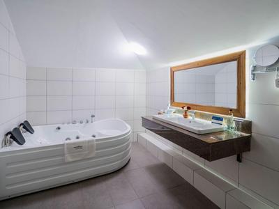 Modern bathroom with large bathtub, sink, and illuminated mirror.