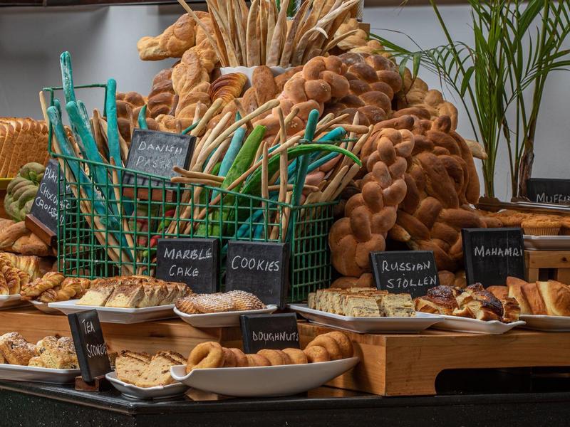 Vielfalt an frischem Gebäck wie Croissants, Brezeln und Brotsorten auf Holztischen präsentiert.