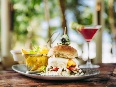 Burger avec olives, frites et cocktail sur une table en bois en plein air