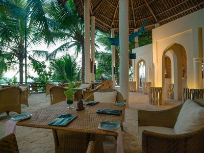 Espace de restauration ouvert avec mobilier en osier et vue sur une végétation tropicale luxuriante.