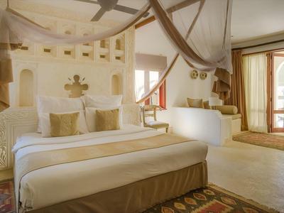 Chambre d'hôtel lumineuse avec grand lit, meubles en bois et porte ouverte sur le jardin