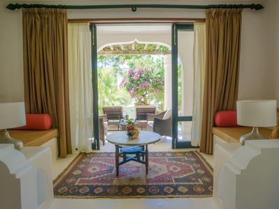 Chambre confortable avec canapés, tapis et vue sur une terrasse avec coin salon et jardin.