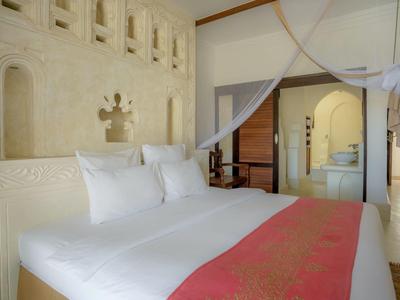 Chambre d'hôtel lumineuse avec grand lit, murs blancs et coureur rouge décoratif.