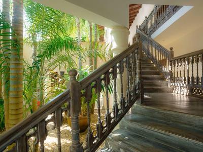 Grand escalier avec rambarde en fer forgé et plantes tropicales dans la cour intérieure.