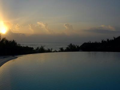 Vue d'une piscine au coucher du soleil avec la mer et un ciel nuageux en arrière-plan