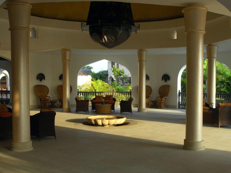 Espace ouvert avec colonnes, sièges et fontaine dans un cadre hôtelier.