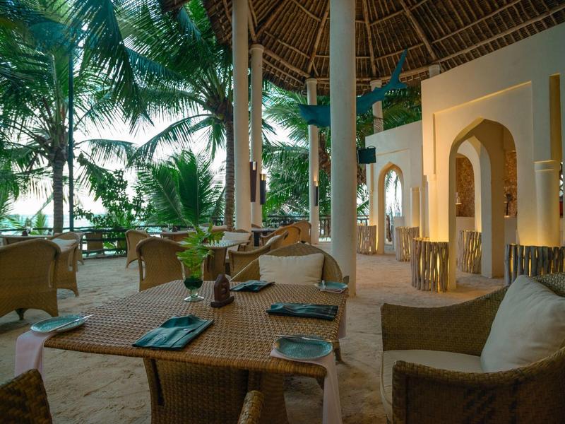 Espace extérieur confortable d'un complexe avec mobilier en osier et végétation tropicale.