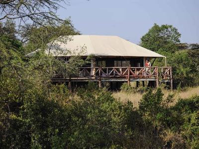 Ein freistehendes Ferienhaus mit Veranda inmitten dichter grüner Vegetation unter klarem Himmel.