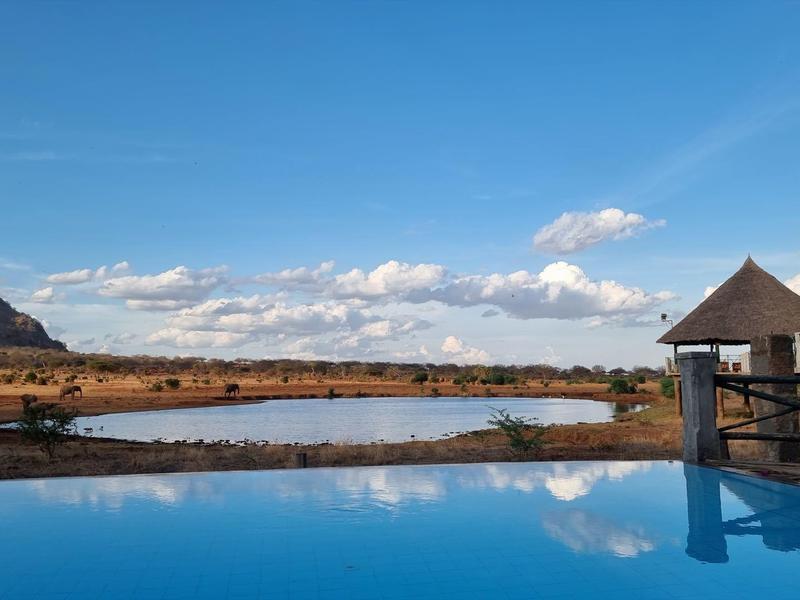 Piscina infinita con vista a paisaje seco y cielo nublado durante el día.