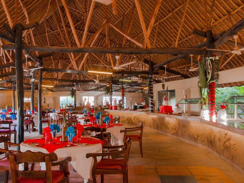 Amplio restaurante con techo de madera, mesas redondas y decoración de mesa en rojo y blanco.