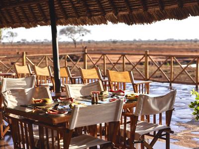Open dining area overlooking a riverbank, natural wooden furniture, and a thatched roof.