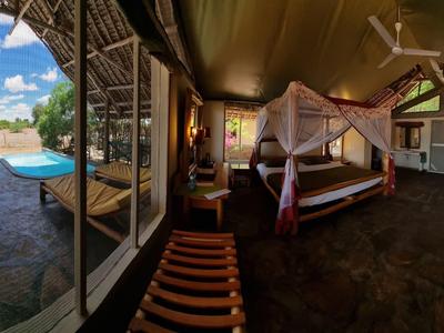 Spacious room with open view, canopy bed, and outdoor terrace in a tropical hotel.