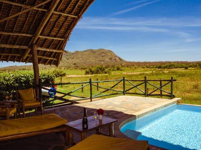 Pool terrace overlooking a vast grassland and hill, covered seating area in the foreground.