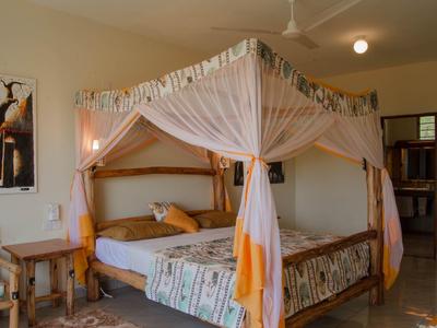 Wooden bed with mosquito net and colorful bedding in a bright hotel room.