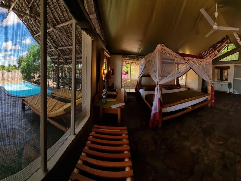 Spacious room with open view, canopy bed, and outdoor terrace in a tropical hotel.