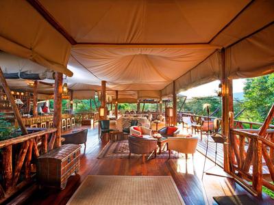 Geräumige, überdachte Terrasse mit Holzmöbeln und Blick auf grüne Natur.