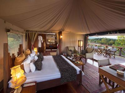Luxuriöses Zelt mit Doppelbett, Sitzecke und Aussicht auf die Natur von einem Balkon.