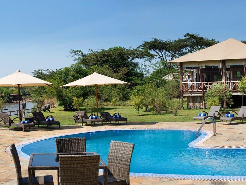 Außenpool mit Liegestühlen, Sonnenschirmen und Sitzbereich in einer Gartenanlage neben einem Hotelgebäude.