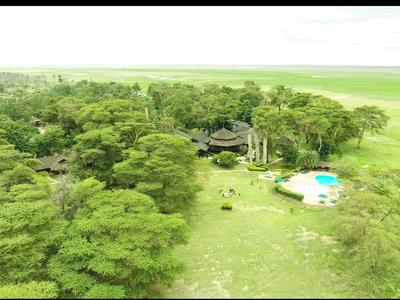 Hotel verde con piscina y bungalows en un paisaje boscoso y extenso cerca del mar.