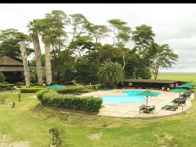 Una piscina redonda con tumbonas, rodeada de césped y árboles bajo un cielo nublado.