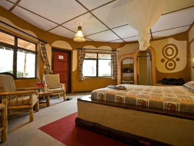 Habitación de hotel acogedora con cama doble, área de estar y tonos cálidos, gran ventana con cortinas.