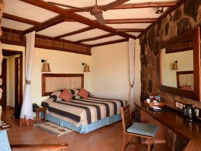 Acogedora habitación de hotel con cama grande, ventilador de techo y muebles de madera.