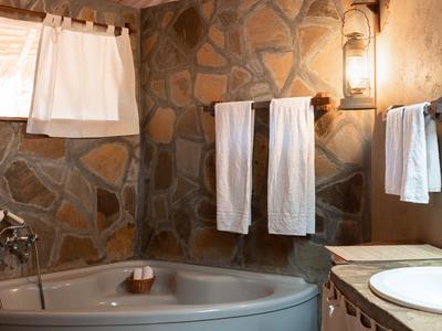 Gemütliches Badezimmer mit Rundbadewanne, Steinwand und weißen Handtüchern.