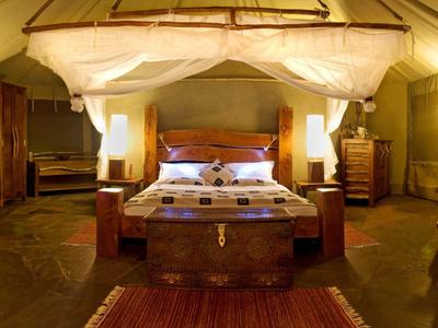 Elegantes Safari-Zelt mit Doppelbett, Moskitonetz und warmem Licht.