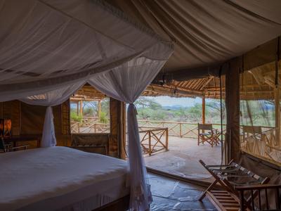 Zimmer mit Himmelbett und offener Terrasse mit Blick auf eine grüne Landschaft.