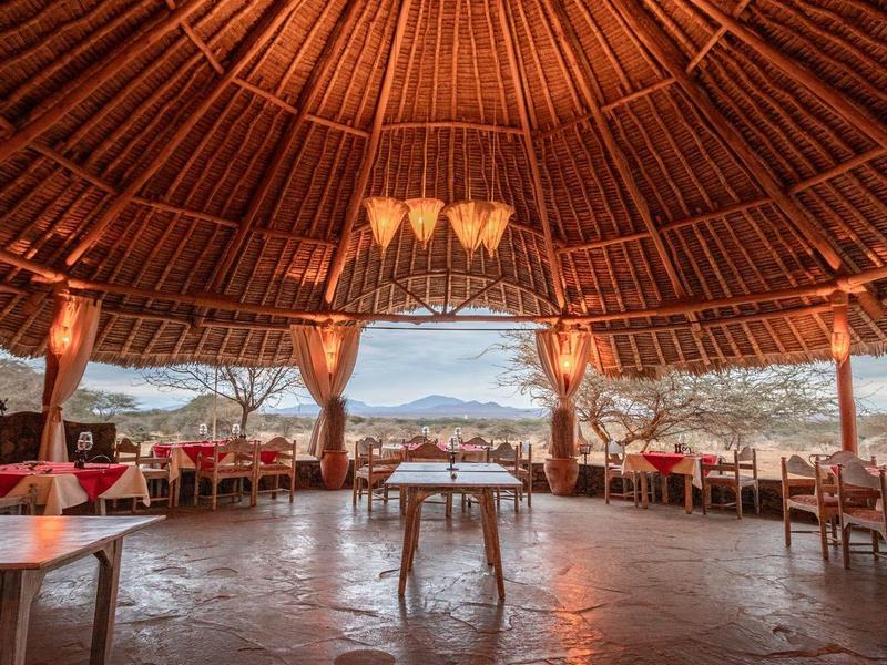 Grand pavillon ouvert avec plafond en bois et vue sur les montagnes et la mer.